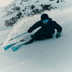 Skier carving a deep powder turn, spraying a wall of snow behind them